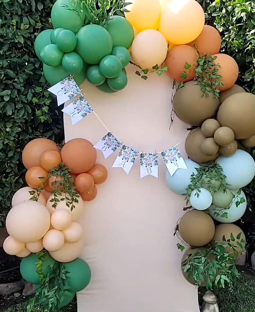 Boho balloon garland in sage green and terracotta with greenery.