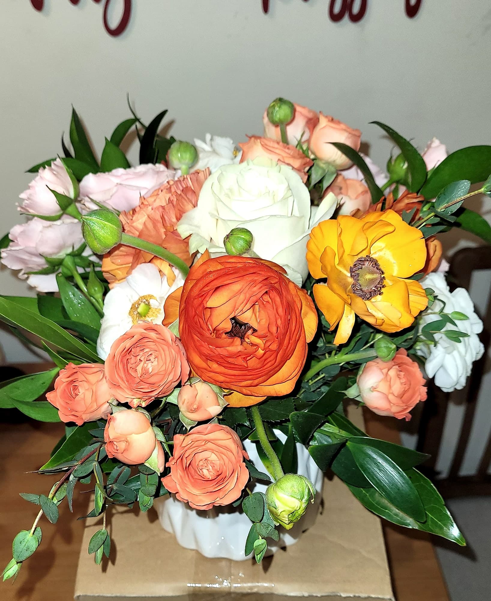 Lush bouquet of orange, peach, and cream ranunculus and garden roses.
